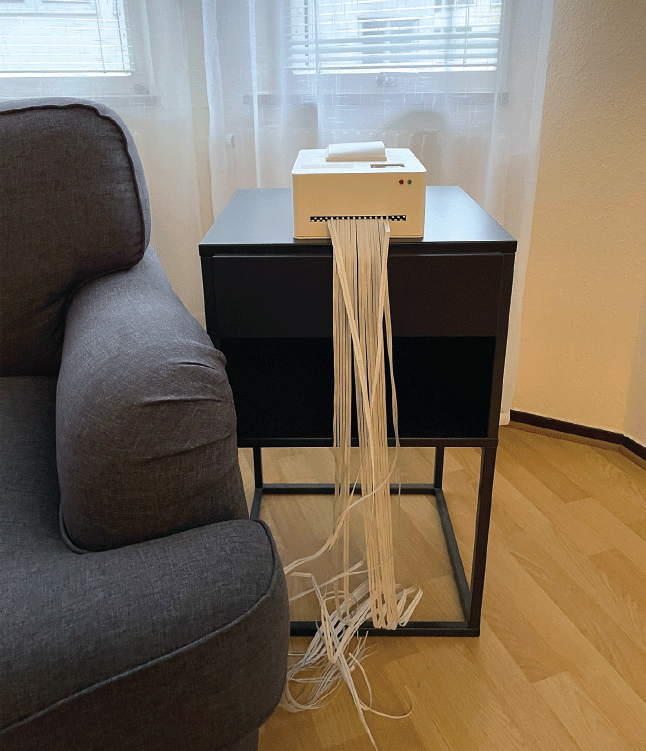 The Shredit design concept shown in a home environment beside a sofa chair with shredded paper.